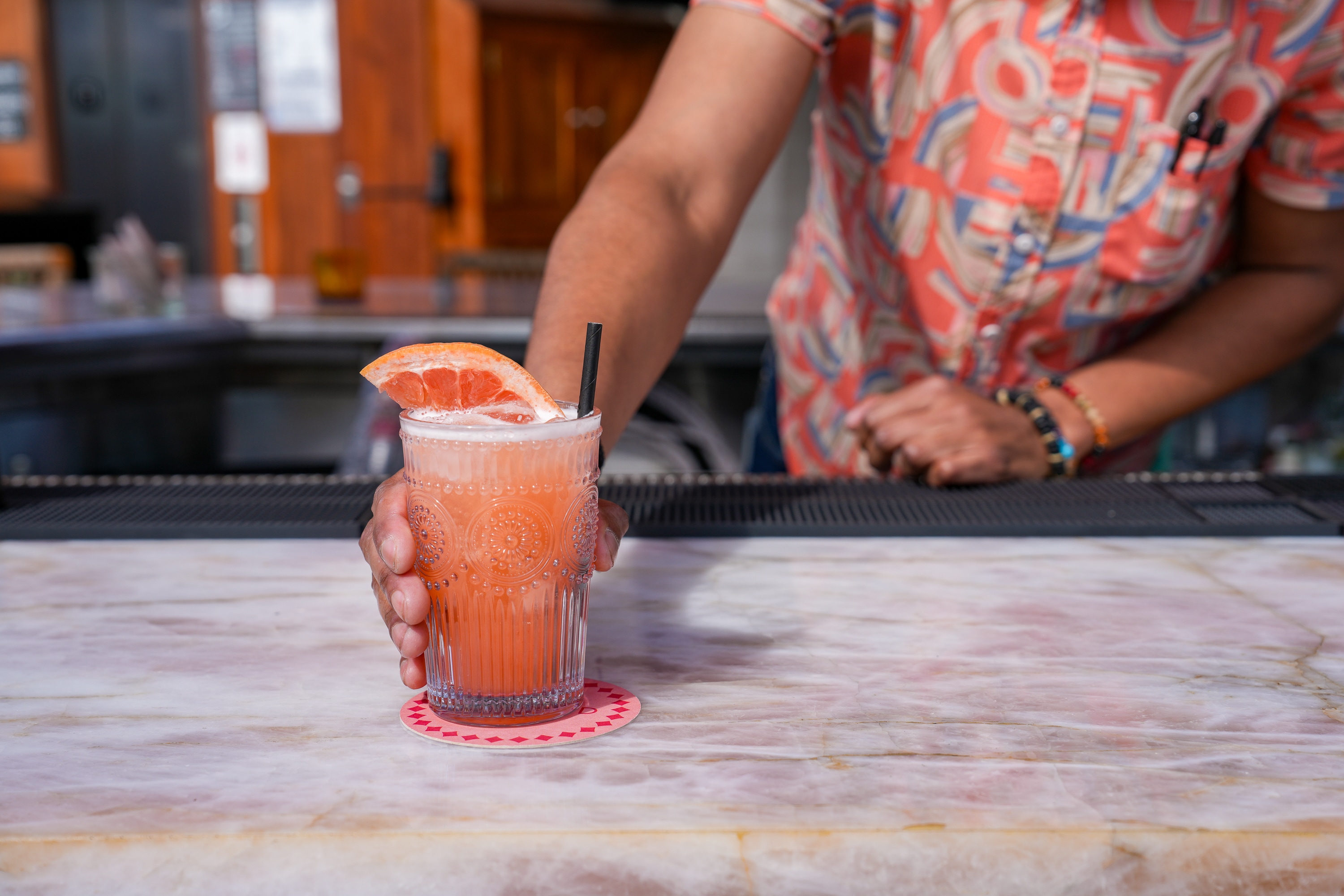 Bartender serving a grapefruit cocktail on the bar at Sunbird Rooftop in San Diego’s Gaslamp Quarter.